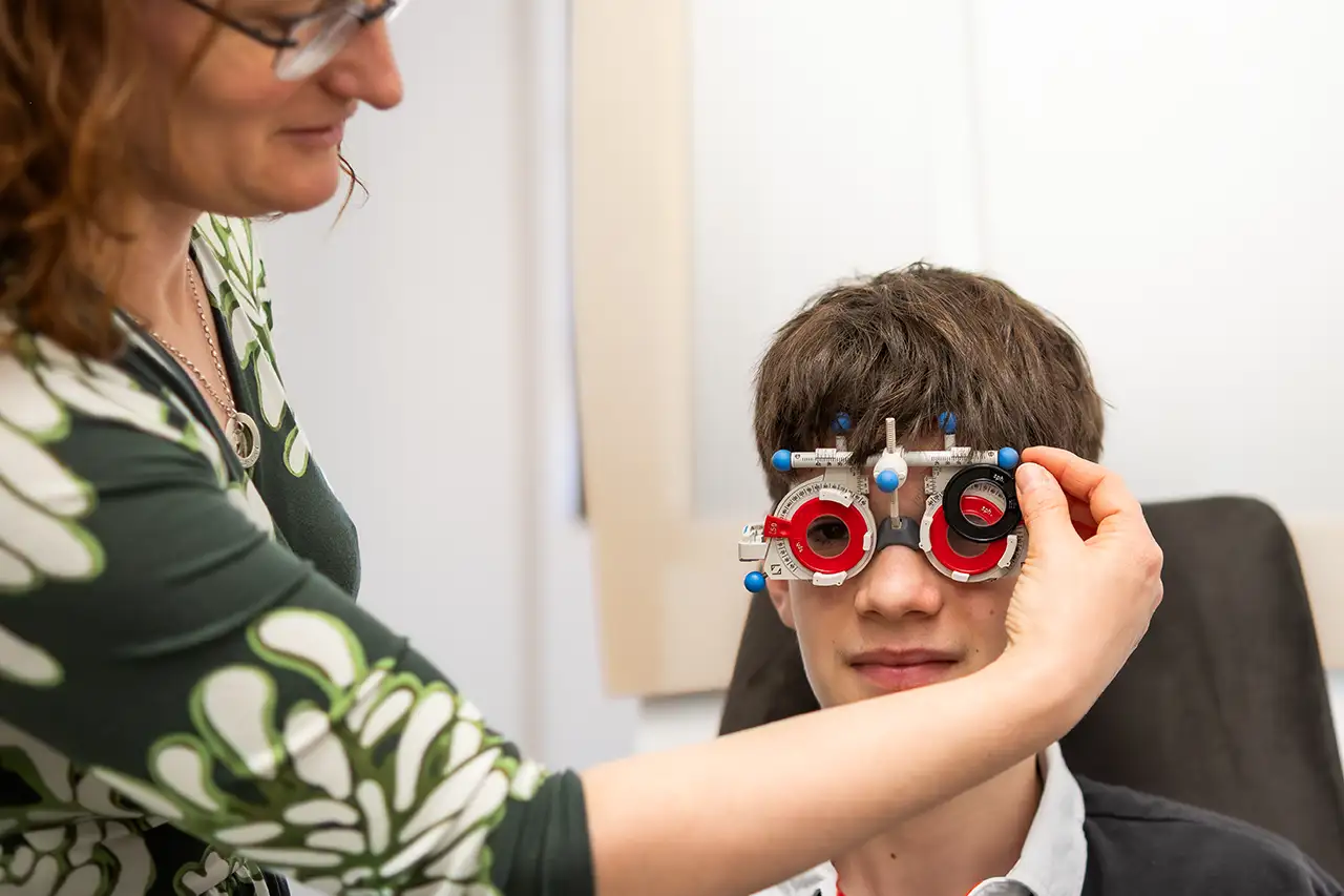 Augenoptikermeisterin Britta Nausch passt einem jungen Mann ein Probiergestell zur Sehstärkenbestimmung an