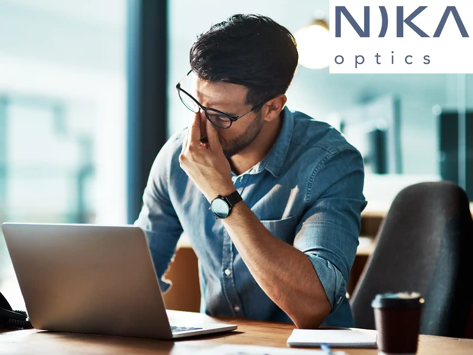 Mann mit Brille reibt sich müde die Augen vor dem Laptop – Symbol für Augenbelastung am Bildschirm
